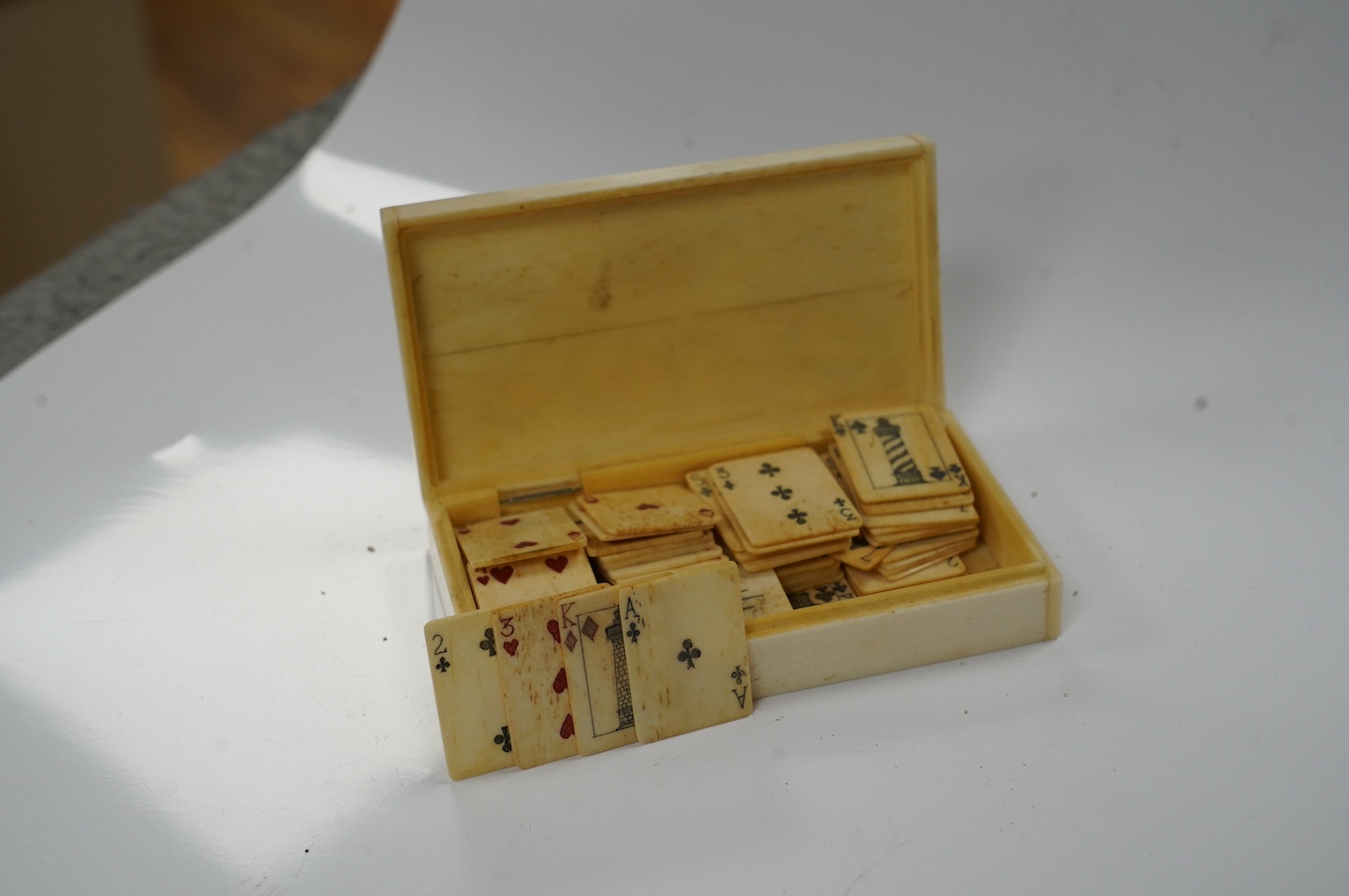 A set of bone scrimshaw type miniature playing cards, in box engraved with a ship and lighthouses, 11cm. Condition - good